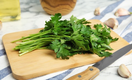Photo of Wooden board with fresh green parsley on table, closeup