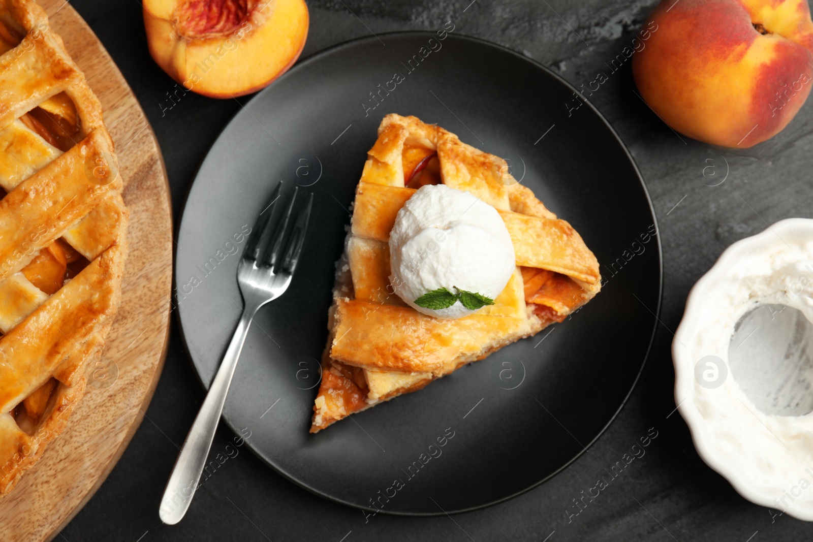 Photo of Slice of delicious peach pie with ice cream on black table, flat lay