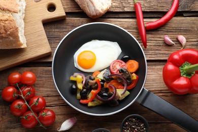 Photo of Tasty fried egg with vegetables in pan and ingredients on wooden table, flat lay