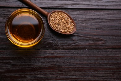 Photo of Bowl of natural oil and mustard seeds on wooden table, flat lay. Space for text