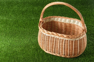 Photo of Empty wicker basket on green lawn, space for text. Easter item