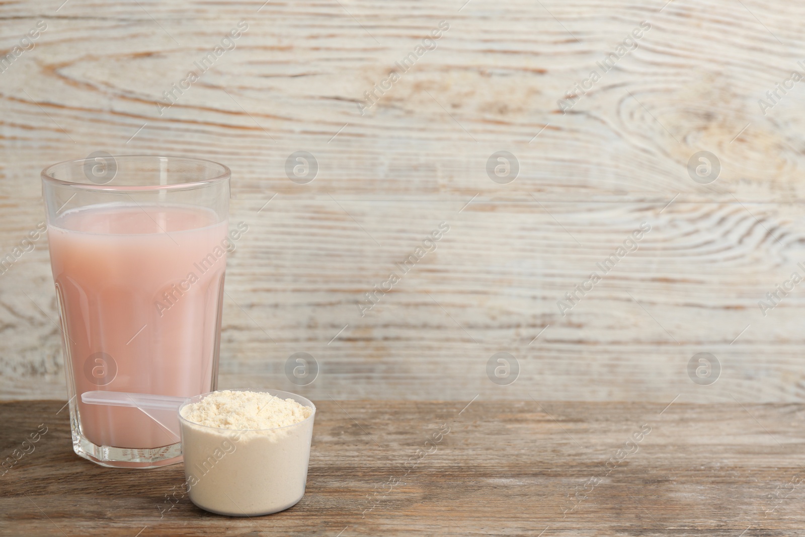 Photo of Protein shake and powder on wooden table, space for text