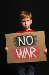 Photo of Boy holding poster No War against black background