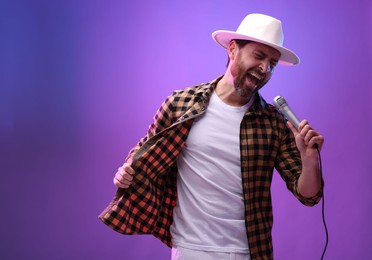 Emotional man with microphone singing in neon lights. Space for text