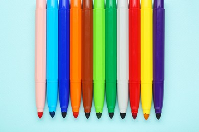 Photo of Different colorful markers on light blue background, flat lay