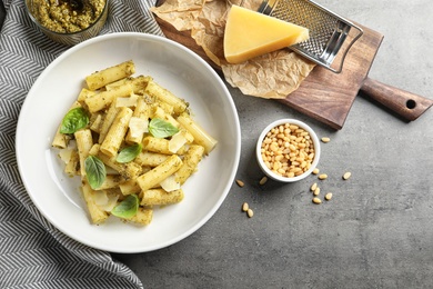 Photo of Flat lay composition with plate of delicious basil pesto pasta on gray table