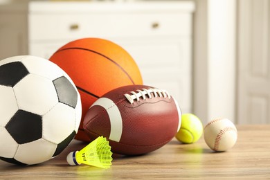 Photo of Set of different sport balls and shuttlecock on wooden table indoors