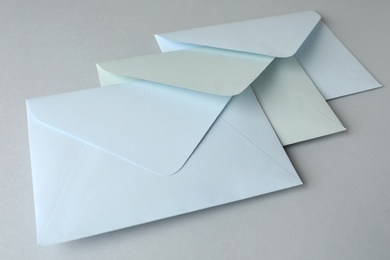 Photo of White paper envelopes on light grey background, closeup. Mail service