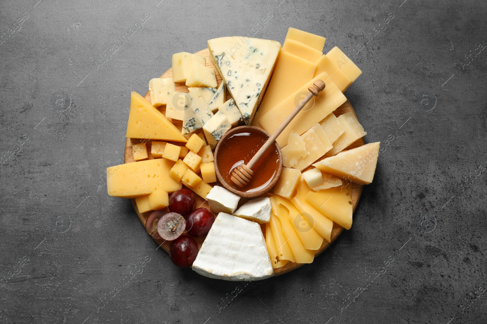 Photo of Different types of delicious cheese and snacks served on grey table, top view