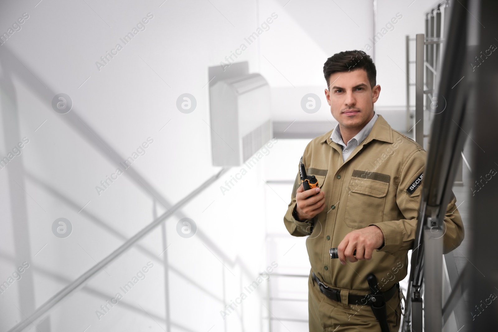 Photo of Professional security guard with portable radio set on stairs. Space for text