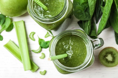 Photo of Delicious green juice and fresh ingredients on white table, flat lay