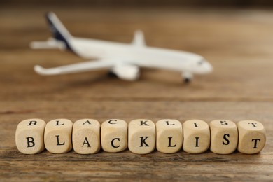 Photo of Cubes with word Blacklist on wooden table, closeup