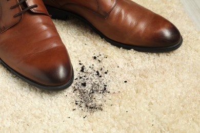 Photo of Brown shoes and mud on beige carpet, closeup