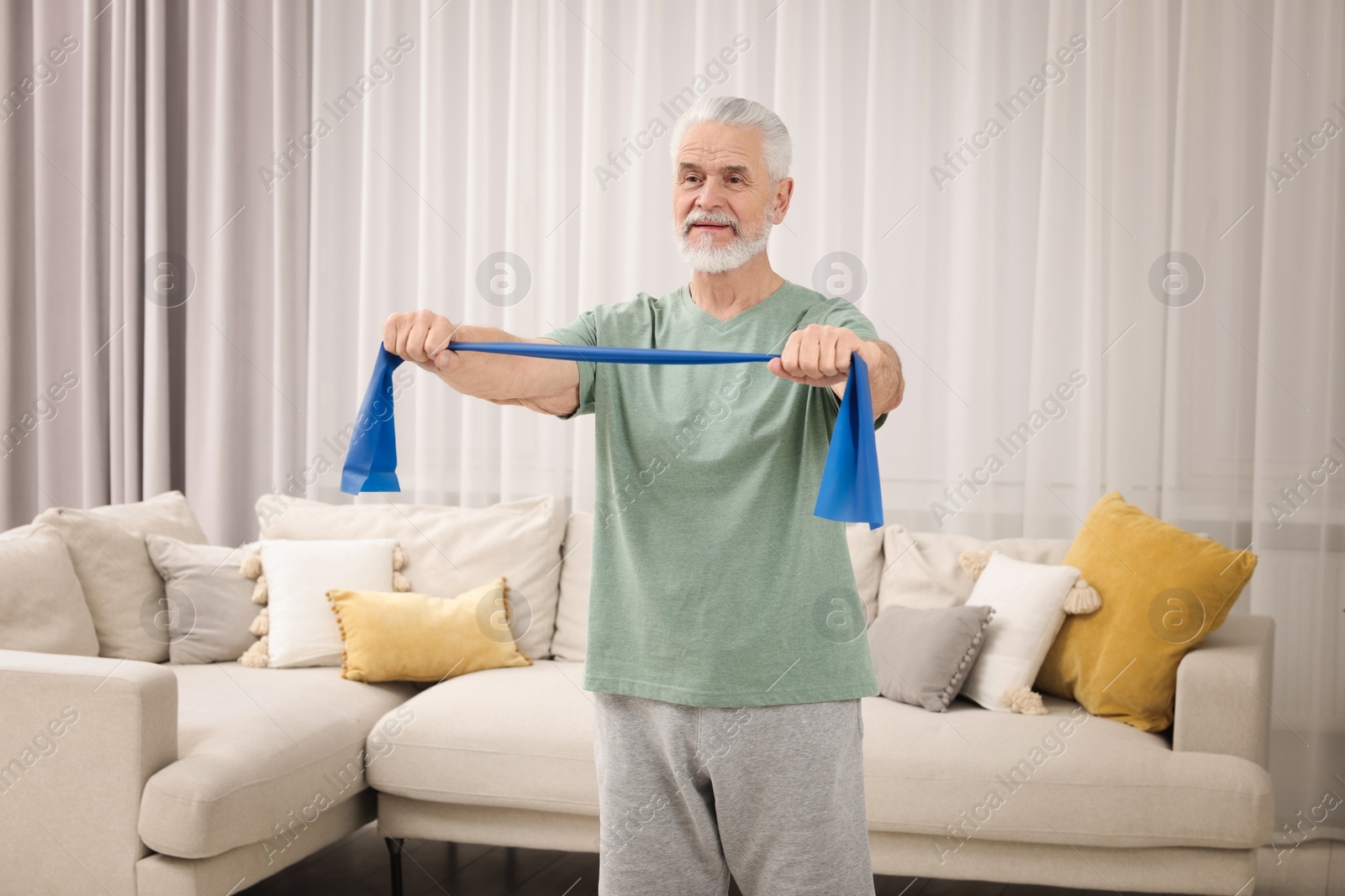 Photo of Senior man doing exercise with fitness elastic band at home