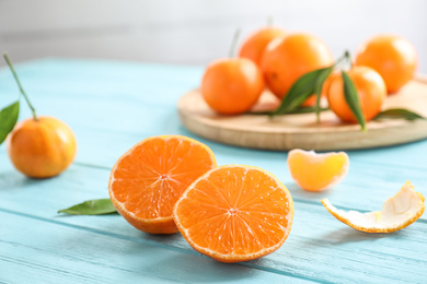 Photo of Cut fresh ripe tangerines on light blue table