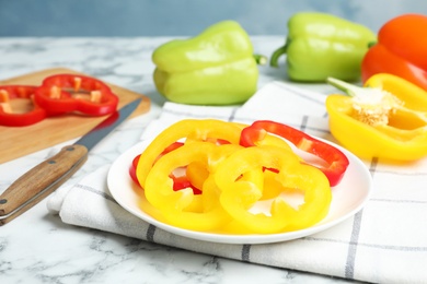 Photo of Plate with cut ripe bell peppers on marble table