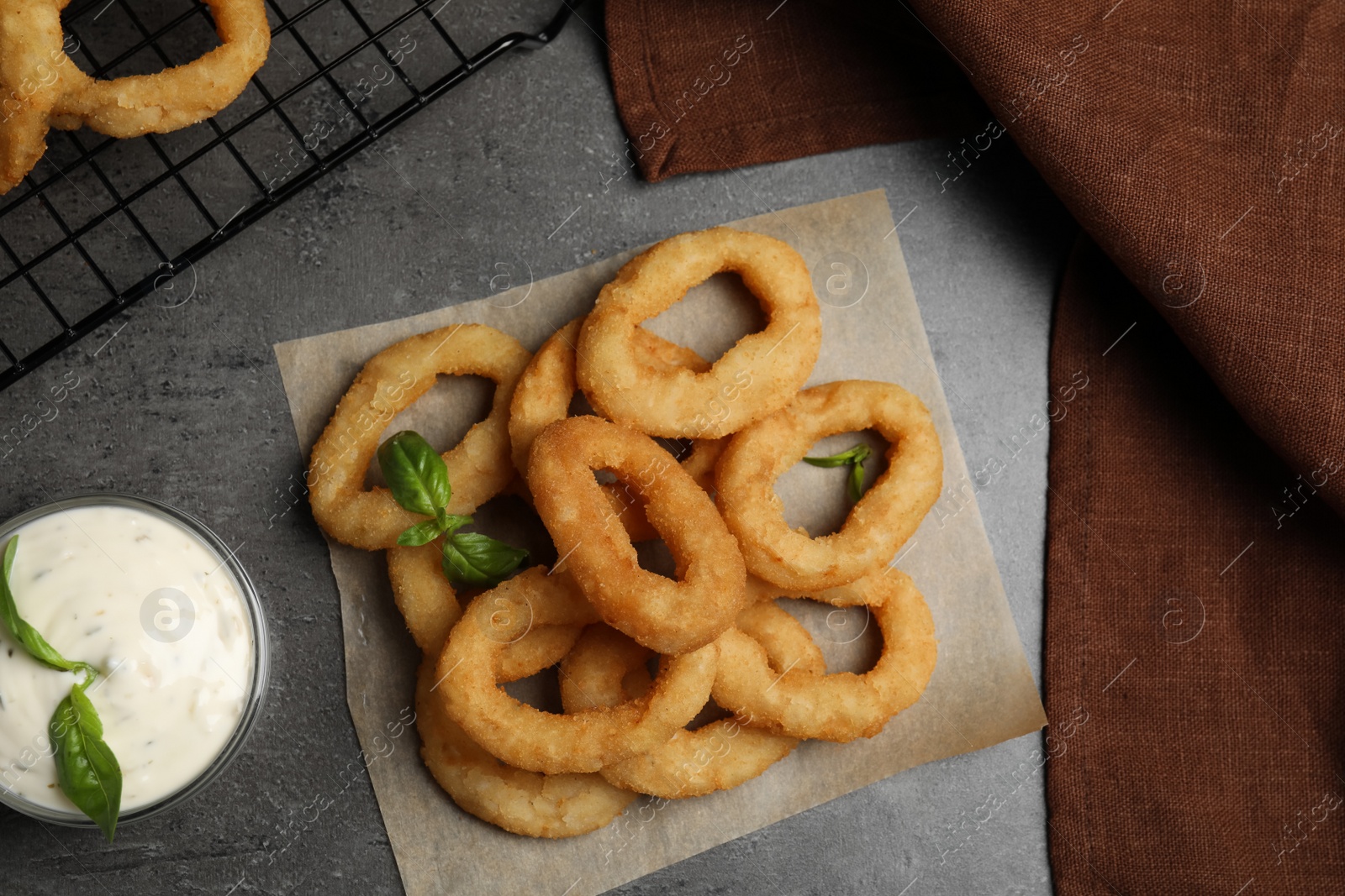 Photo of Fried onion rings served on grey table, flat lay