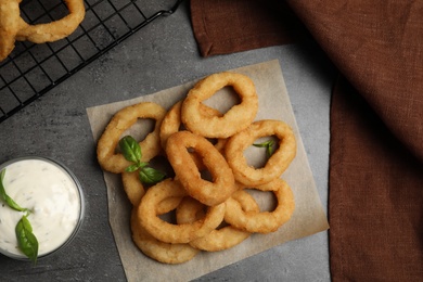 Photo of Fried onion rings served on grey table, flat lay