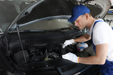 Photo of Professional auto mechanic fixing modern car in service center