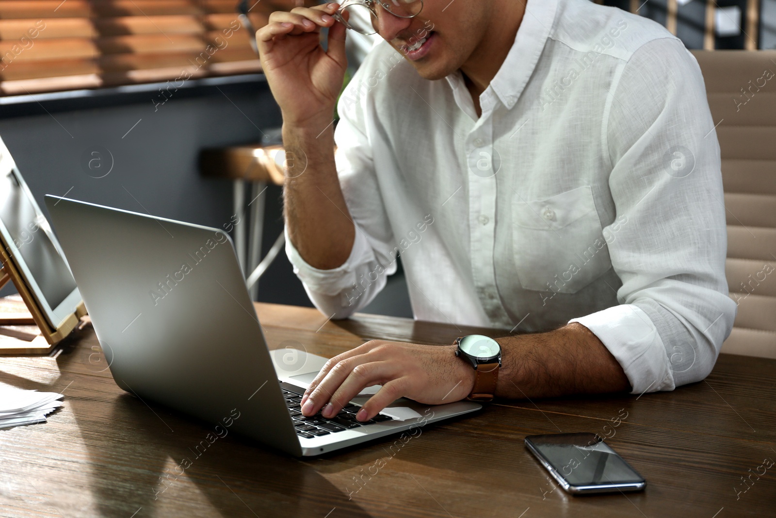 Photo of Freelancer working on laptop at table indoors, closeup