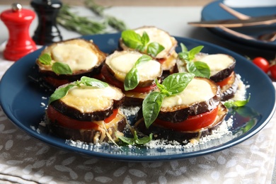 Photo of Baked eggplant with tomatoes, cheese and basil on table, closeup