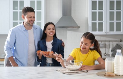 Happy family cooking together at table in kitchen. Adoption concept