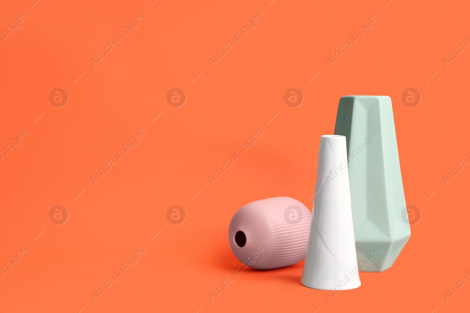 Photo of Stylish empty ceramic vases on orange background, space for text