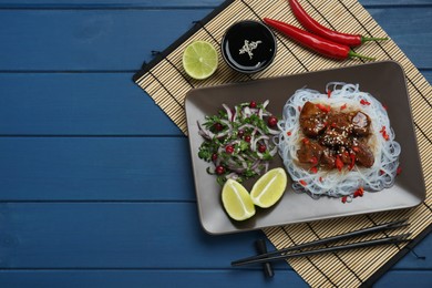 Photo of Pieces of soy sauce chicken with noodle, salad and lime served on blue wooden table, flat lay
