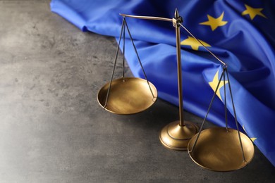 Photo of Scales of justice and European Union flag on grey table, above view. Space for text