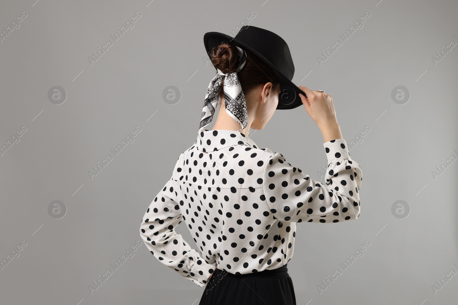 Photo of Woman with black hat and stylish bandana on light grey background