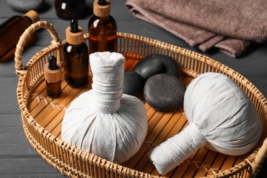 Herbal massage bags, essential oils and spa stones on grey wooden table