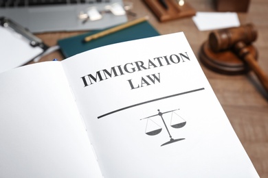 Photo of Book with words IMMIGRATION LAW on table, closeup