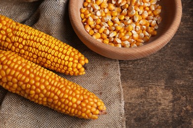 Delicious ripe corn cobs and bowl with seeds on wooden table