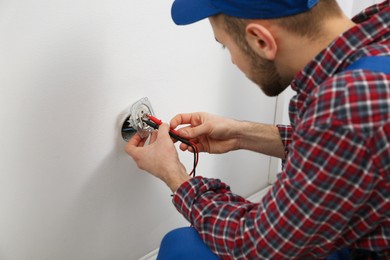 Photo of Electrician with tester checking voltage, closeup view