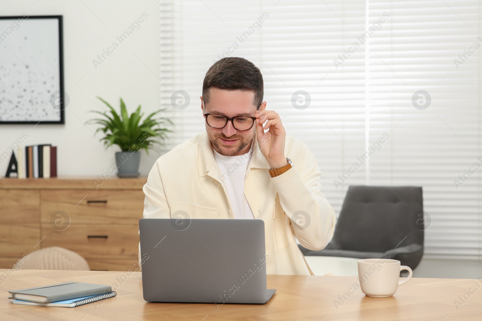 Photo of Man working with laptop at wooden table at home