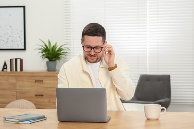 Man working with laptop at wooden table at home