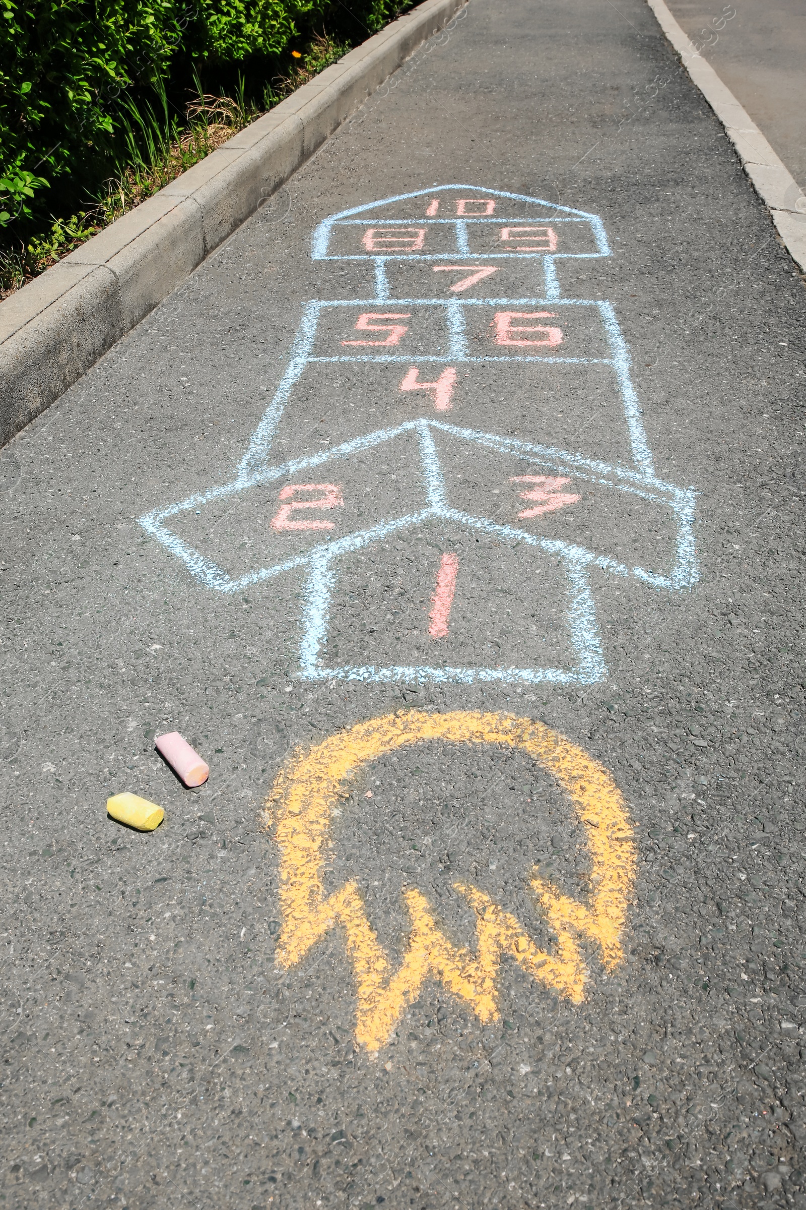 Photo of Hopscotch drawn with colorful chalk on asphalt outdoors, closeup