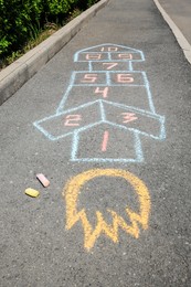 Photo of Hopscotch drawn with colorful chalk on asphalt outdoors, closeup