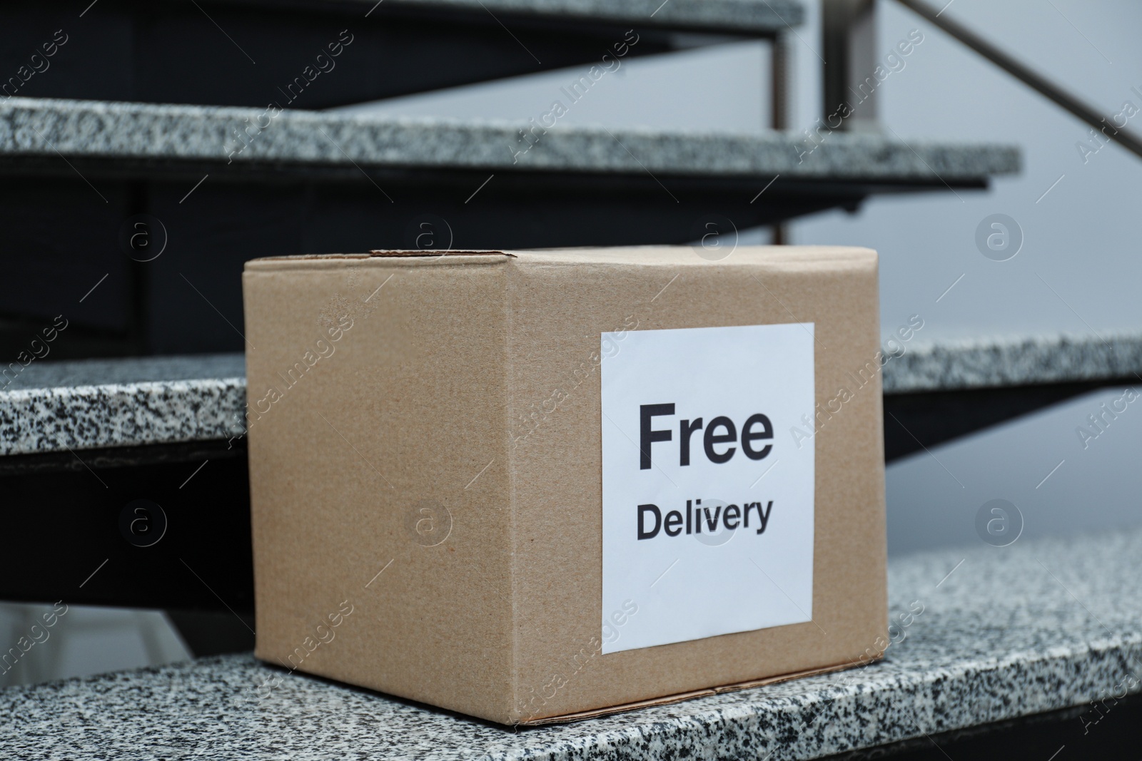Photo of Parcel with sticker Free Delivery on stairs. Courier service