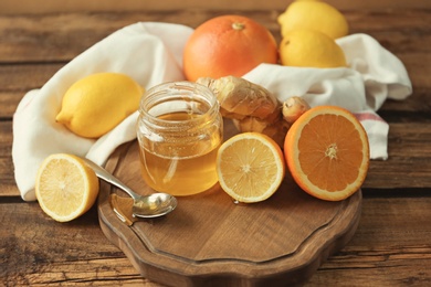 Photo of Citrus fruits, ginger and jar with honey on wooden table