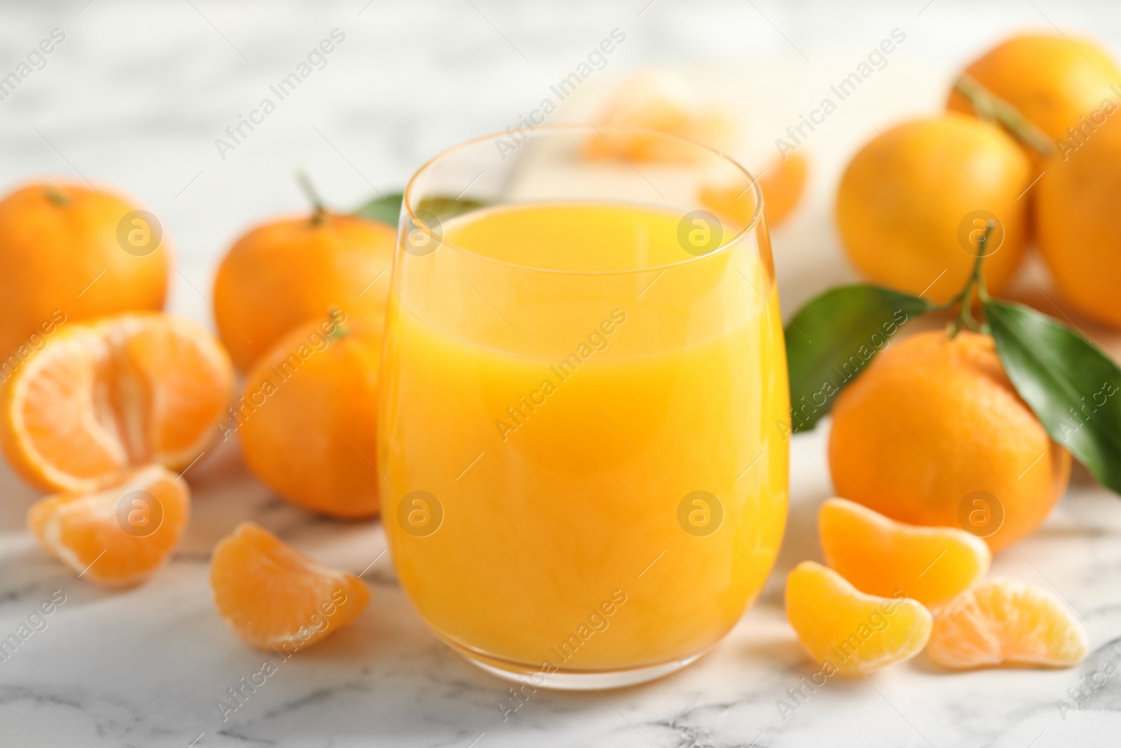 Photo of Glass of fresh tangerine juice and fruits on marble table