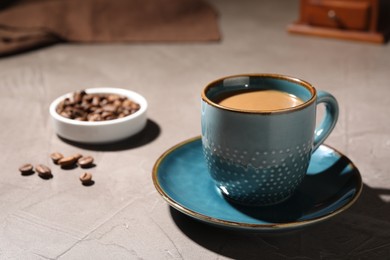 Photo of Delicious coffee with milk in cup and beans on light textured table, closeup. Space for text