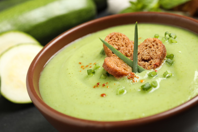 Photo of Tasty homemade zucchini cream soup in bowl on table, closeup