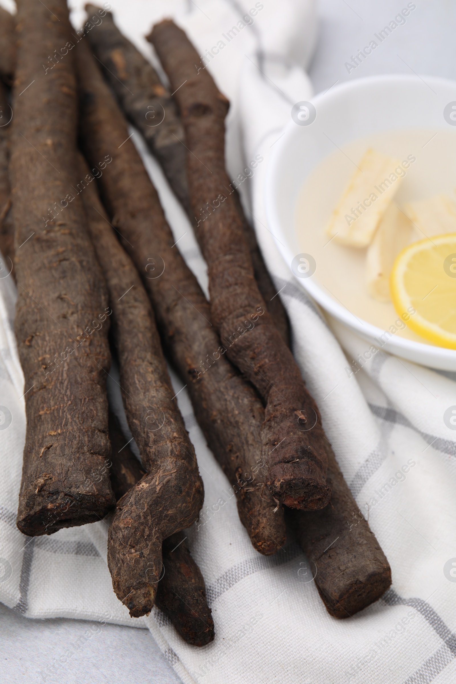 Photo of Raw salsify roots and bowl with lemon on white table