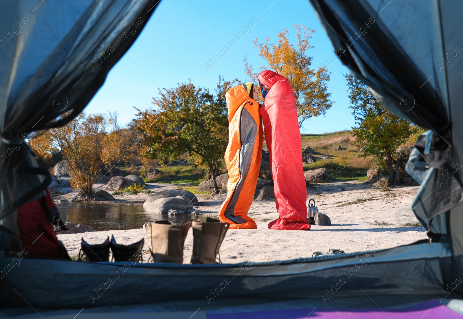 Photo of Cute couple in sleeping bags outdoors, view from camping tent