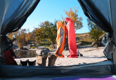 Photo of Cute couple in sleeping bags outdoors, view from camping tent
