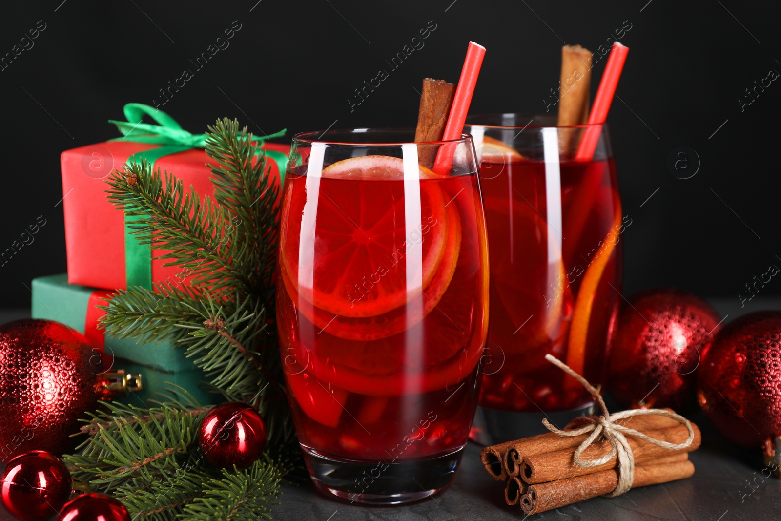 Photo of Delicious Sangria drink in glasses and Christmas decorations on dark table, closeup