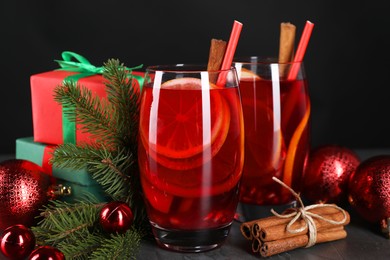 Delicious Sangria drink in glasses and Christmas decorations on dark table, closeup