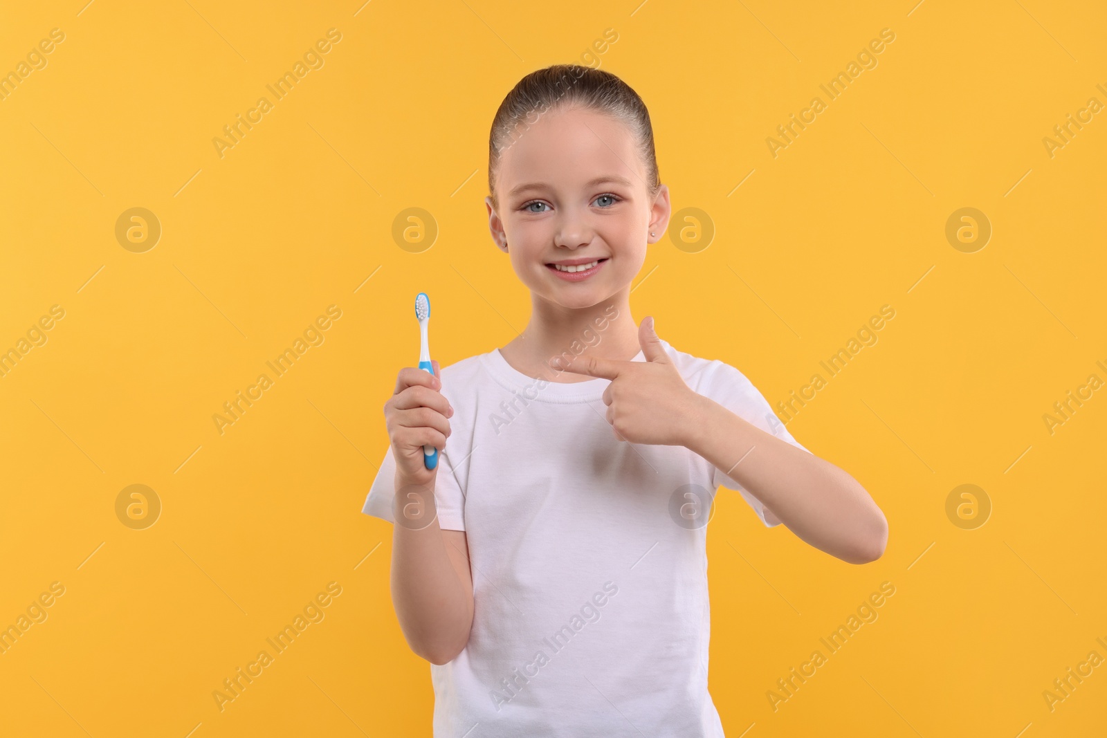 Photo of Happy girl holding toothbrush on yellow background