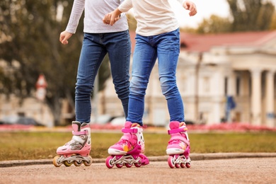 Photo of Children roller skating on city street, focus on legs